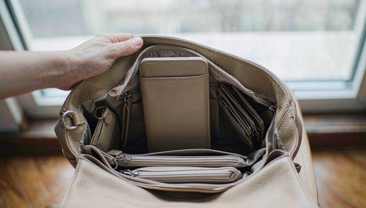Interior of an open leather handbag showing a phone slip pocket, zip pocket and key leash