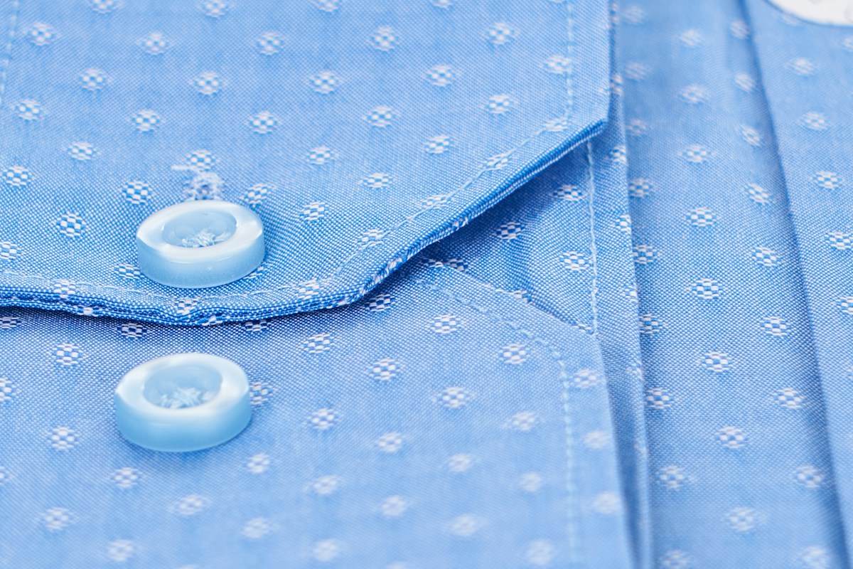 A close-up of a pale blue cotton shirt showing the collar and buttons